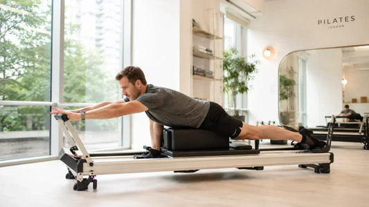 Person stretching on a reformer Pilates machine to improve flexibility and mobility in a modern studio