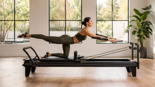 Person using a Pilates reformer machine to strengthen core, legs, arms, back, and glute muscles in a modern studio